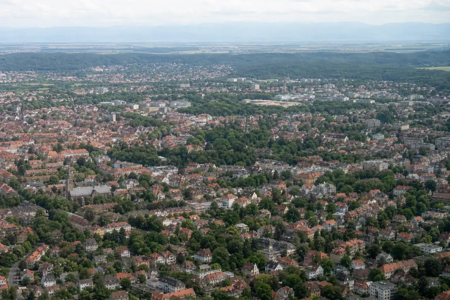 Vue aérienne discrète de l’agglomération strasbourgeoise, toits et végétation